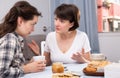 Emotional women having conflict at table with coffee in home