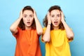 Emotional women with wide open eyes, holding heads on blue background Royalty Free Stock Photo