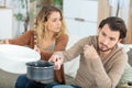 emotional young couple collecting water leaking from ceiling