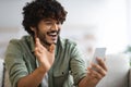 Emotional hindu guy having online party with friends, using smartphone