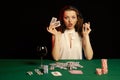 Emotional young lady in a white blouse drinking wine from a glass and playing cards Royalty Free Stock Photo