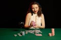 Emotional young lady in a white blouse drinking wine from a glass and playing cards Royalty Free Stock Photo