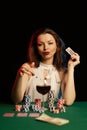 Emotional young lady in a white blouse drinking wine from a glass and playing cards Royalty Free Stock Photo