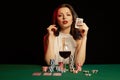 Emotional young lady in a white blouse drinking wine from a glass and playing cards Royalty Free Stock Photo