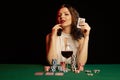 Emotional young lady in a white blouse drinking wine from a glass and playing cards Royalty Free Stock Photo