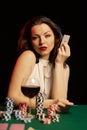 Emotional young lady in a white blouse drinking wine from a glass and playing cards Royalty Free Stock Photo