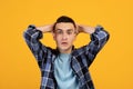 Emotional young man grabbing his head in shock, looking at camera on orange studio background. Human emotions Royalty Free Stock Photo