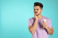 Emotional young man with sensitive teeth and ice cream on color background. Royalty Free Stock Photo