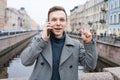 Emotional young man using mobile phone, wearing an elegant gray coat, stands Royalty Free Stock Photo