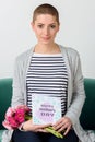 Emotional young mother holding bouquet of gerbera daisies and reading her mother`s day card. Royalty Free Stock Photo