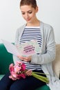 Emotional young mother holding bouquet of gerbera daisies and reading her mother`s day card. Royalty Free Stock Photo