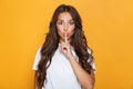 Emotional young pretty woman posing isolated over yellow background showing silence gesture.