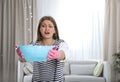 Emotional young woman collecting water leaking from ceiling in living room Royalty Free Stock Photo