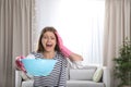 Emotional young woman collecting water leaking from ceiling in living room. Royalty Free Stock Photo