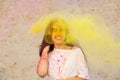 Emotional young model having fun in a cloud of yellow dry powder, celebrating Holi colors festival at the desert Royalty Free Stock Photo