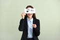 Emotional young woman hiding face behind sheet of paper with drawn eyes on light background Royalty Free Stock Photo