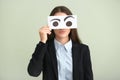 Emotional young woman hiding face behind sheet of paper with drawn eyes on light background Royalty Free Stock Photo