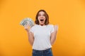 Emotional young woman holding money make winner gesture.