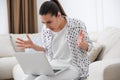 Emotional young woman with laptop at home. Online hate