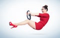 Emotional young woman in a red dress and glasses is driving a car steering wheel, auto concept Royalty Free Stock Photo
