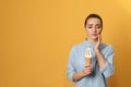 Emotional young woman with sensitive teeth and ice cream on color background