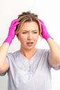 The emotionally shocked young female medical worker holding hands on her head fell into panic on white background Royalty Free Stock Photo