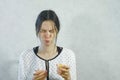 Emotions from the sour on the girl`s face. Brunette woman eating sour tangerine and wincing. Royalty Free Stock Photo