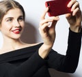 Emotions, expressions and people concept - happy smiling young woman wearing black dress taking selfie with smartphone