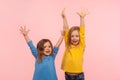 Emotions of happy winners children. Two enthusiastic lively energetic little girls standing with raised hands Royalty Free Stock Photo