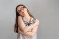 Emotions and people. A young brunette woman in glasses and a blouse, closing her eyes, hugs herself by the shoulders. Emotion of Royalty Free Stock Photo