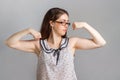 Emotions and people. A young woman in a blouse and glasses flexed her muscles, showing her strength and willingness to work Royalty Free Stock Photo