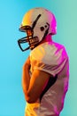 Portrait of one American football player in sports equipment helmet and gloves isolated on blue studio background in Royalty Free Stock Photo