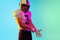 Portrait of one American football player in sports equipment helmet and gloves isolated on blue studio background in Royalty Free Stock Photo