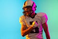 Portrait of one American football player in sports equipment helmet and gloves isolated on blue studio background in Royalty Free Stock Photo