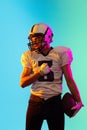 Portrait of one American football player in sports equipment helmet and gloves isolated on blue studio background in Royalty Free Stock Photo