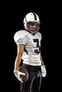 Portrait of one American football player in sports equipment helmet and gloves isolated on dark studio background Royalty Free Stock Photo