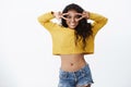 Emotions and wellbeing concept. Cheerful african-american curly-haired girl in cropped yellow sweater, jeans showing