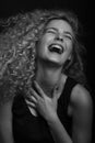 Emotive black and white studio portrait of cute young woman with curly hair. Royalty Free Stock Photo