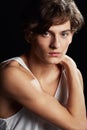 Emotive eyes set in a youthful face. Portrait of a fresh-faced young man wearing a vest while posing against a black