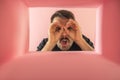 Emotive man looking inside carton box with shock. Royalty Free Stock Photo