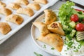 Empanadas with ground beef, cheese filling and side salad on a plate on light background with sheet pan