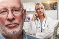 Doctor Standing Behind Troubled Senior Adult Man In Office
