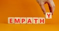 Empathy symbol. The concept word Empathy on wooden cubes. Beautiful orange table, orange background, copy space. Businessman hand