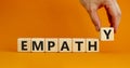 Empathy symbol. The concept word Empathy on wooden cubes. Beautiful orange table, orange background, copy space. Businessman hand