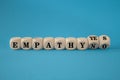 Empathy yes or no symbol. Turned wooden cubes and changes words empathy no to empathy yes on a beautiful blue background. Royalty Free Stock Photo