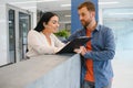 The employee of the beauty salon meets the client in the reception of a modern beauty salon. A man signs a paper with Royalty Free Stock Photo