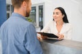 The employee of the beauty salon meets the client in the reception of a modern beauty salon. A man signs a paper with Royalty Free Stock Photo