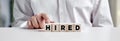 Employee business person pressing his finger on the wooden cubes with the word hired. recruitment and job employment Royalty Free Stock Photo