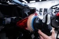 Employee of a car detailing studio polishes the paint of a car