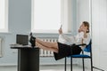 Employee care. Relaxed happy young business woman entrepreneur put legs on table, talking on cell phone, drinking coffee Royalty Free Stock Photo